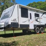Redfoot Levelling - A black and white motorhome parked on grass with Redfoot Levelling Camper Levellers.